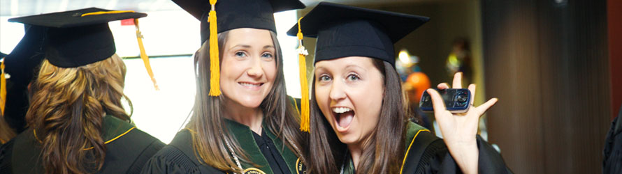 sul_74 two woman looking excited in graduation caps and gowns